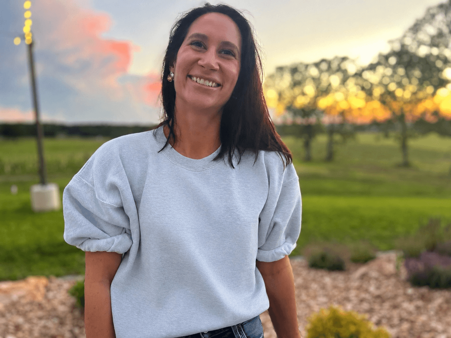 Jonna Steelman smiling outdoors at golden hour, rural Missouri landscape behind her